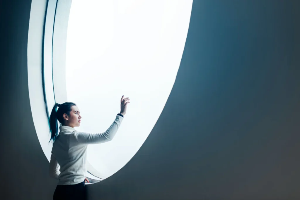 Woman reaching towards large window.