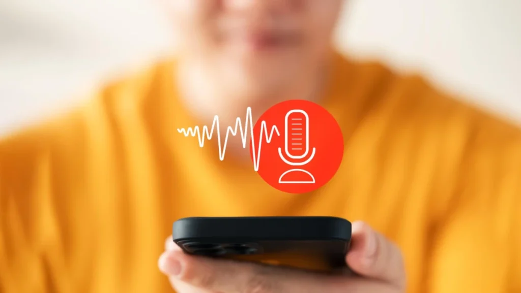 Person in a yellow shirt holding a smartphone with a red voice assistant icon and soundwave graphic displayed, symbolizing voice command or recording.