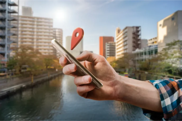 Hand holding smartphone with location pin